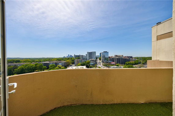 Panoramic view from a balcony, showing a cityscape with tall buildings and a road leading into the distance.