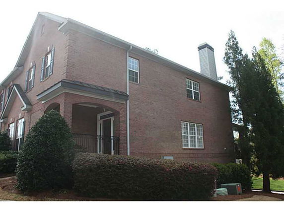 Side view of a two-story brick house with a chimney.