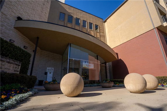 Front view of a building with a modern entrance and large spherical sculptures.