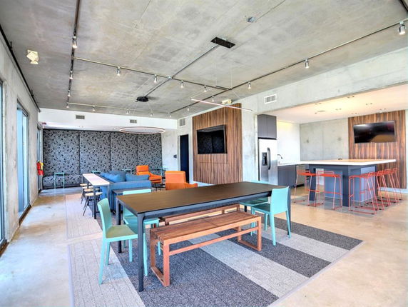 Interior view of a modern clubhouse with tables, chairs, and lounge area.
