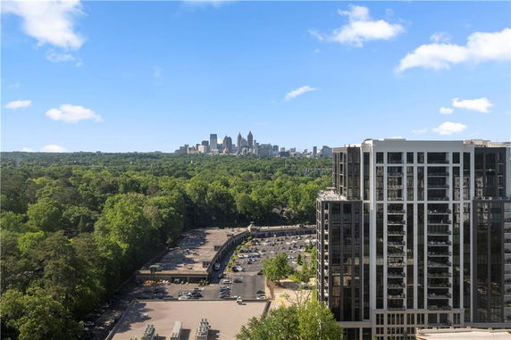 Panoramic view of a cityscape with buildings and a green landscape.