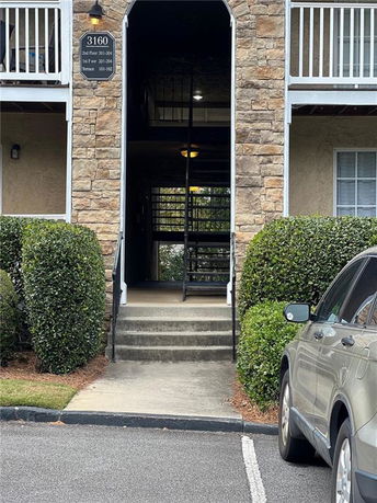 Front view of a building entrance with stone facade and staircase leading inside.