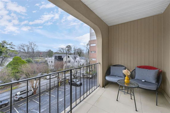 View from a balcony with seating, overlooking a street and neighboring houses.