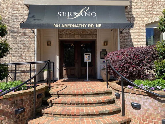 Front view of a building entrance with brick steps and an awning displaying the address.