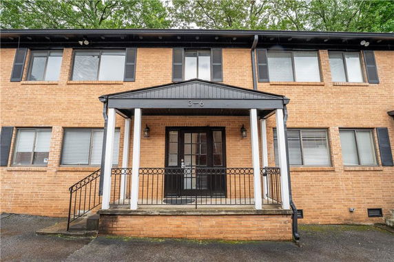 Front view of a two-story brick building with a central entrance and black window shutters.