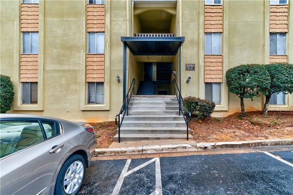 Front view of an apartment building entrance with stairs and a covered entrance.