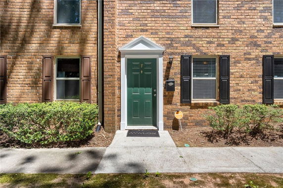 Front view of a house with a green door and brown brick exterior.