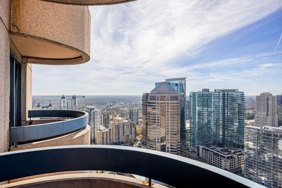 Panoramic view of city buildings from a high-rise balcony.