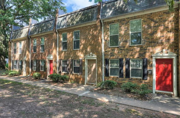 Front view of a row of two-story brick townhouses with various colored doors.