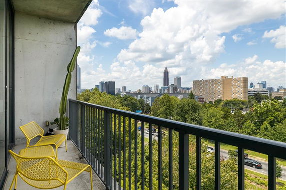 Balcony view of a city skyline with trees and buildings in the distance.