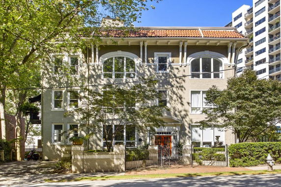 Front view of a multi-story building with a decorative roof and several windows.