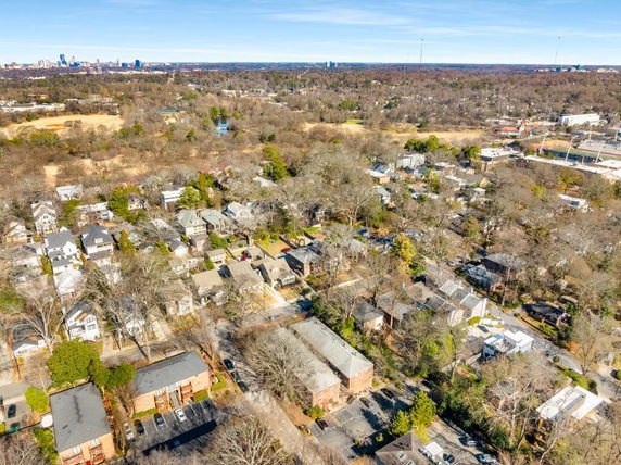 Panoramic view of residential neighborhood with various houses and a city skyline in the background.