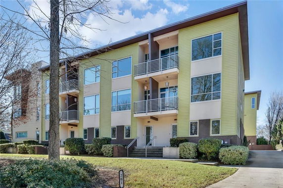 Front view of a modern three-story apartment building with large windows and balconies.