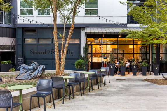 Front view of an outdoor café with seating and decorative plants.