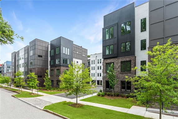 Front view of modern multi-story apartment buildings with large windows and brick facade.