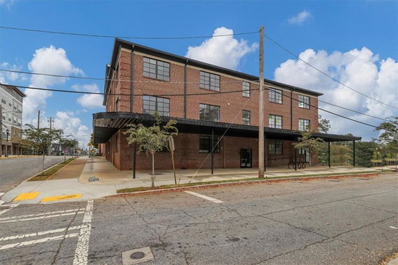 Front view of a three-story brick building with large windows and a black awning.