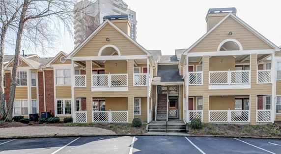 Front view of a two-story apartment building with balconies and a central staircase.