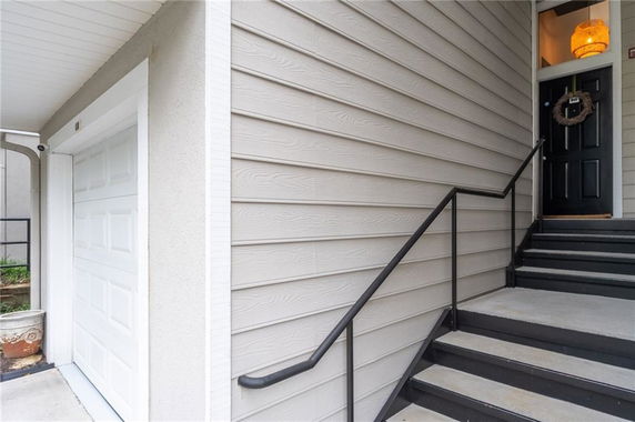 Entrance area with stairs leading to a door next to a garage door.