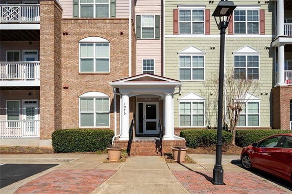Front view of a multi-story residential building with columns and brick facade.