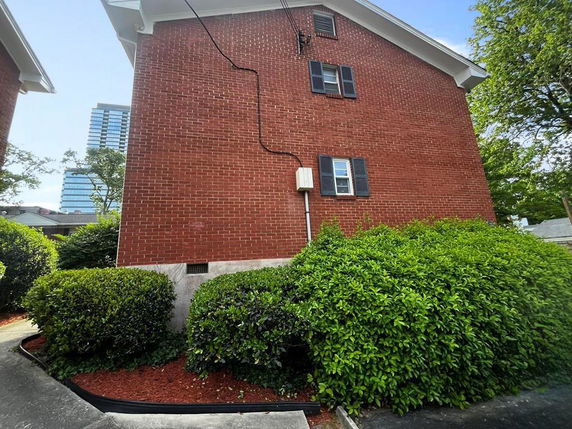 Side view of a red brick building with black window shutters.