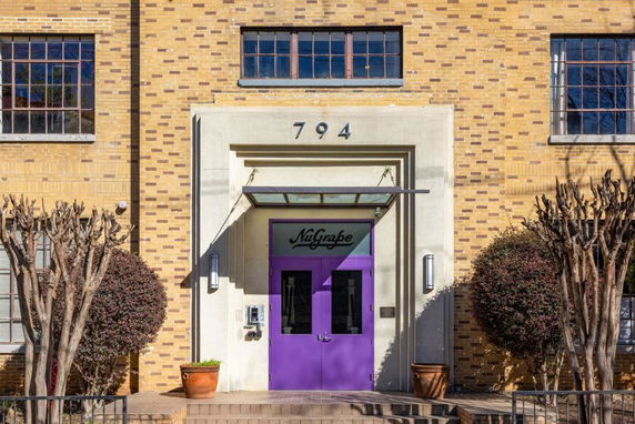 Front view of a building with yellow brick facade and a purple door.