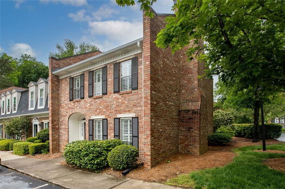 Front view of a two-story brick townhouse with black shutters and white trim.