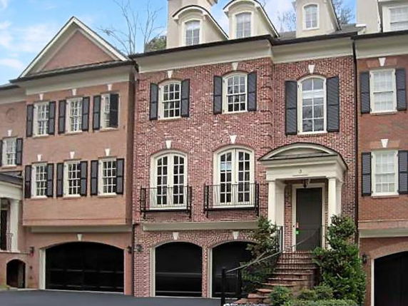 Front view of a three-story brick townhouse with multiple windows and a double garage.