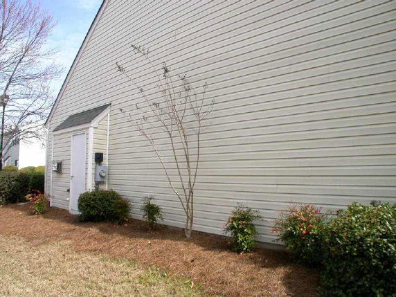 Side view of a building with beige siding and a sloped roof.