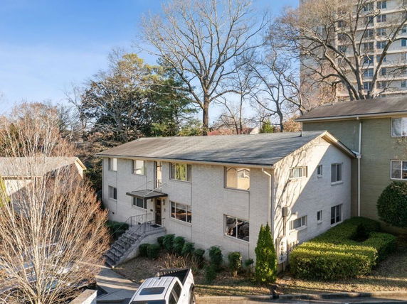 Front view of a two-story house with a sloped roof and a small staircase leading to the entrance.