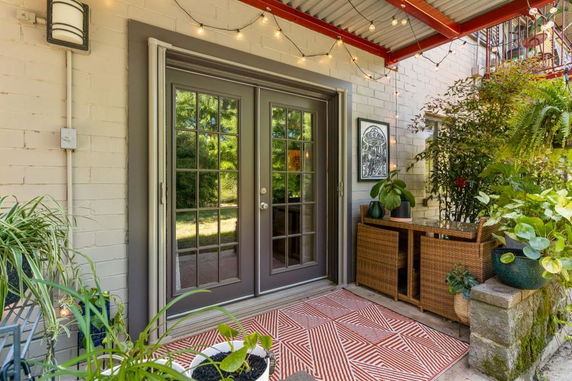 Outdoor area with double doors, plants, and decorative lighting.