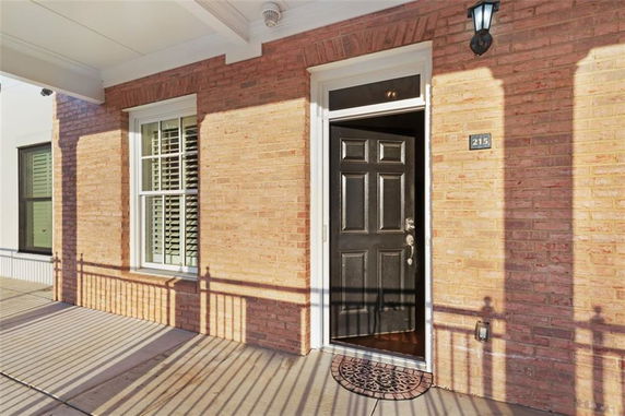 Front view of a brick house with a black door and window with shutters.