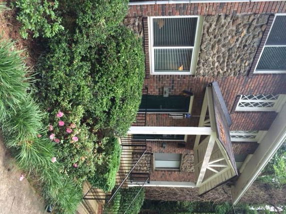 Front view of a brick house with a small porch and shrubs.