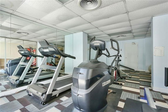 Interior view of a gym with exercise equipment and mirrored walls.