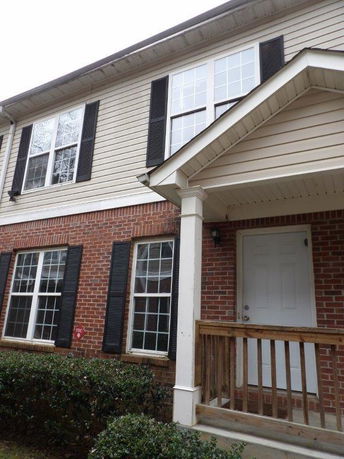 Front view of a two-story house with brick and siding exterior and a small porch.