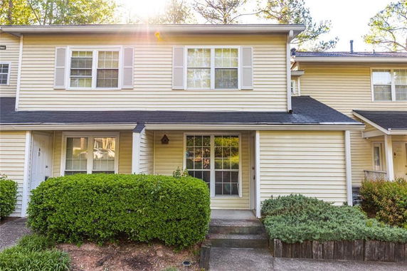 Front view of a two-story townhouse with beige siding and a small front garden.