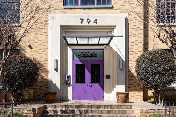 Front view of a brick building entrance with a purple door and glass canopy.