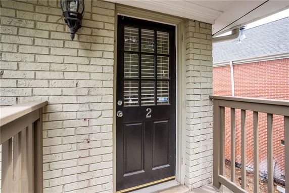 Front view of a door on a brick building with balcony railing.