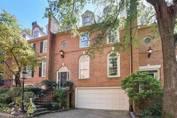Front view of a multi-story brick townhouse with a garage and decorative windows.