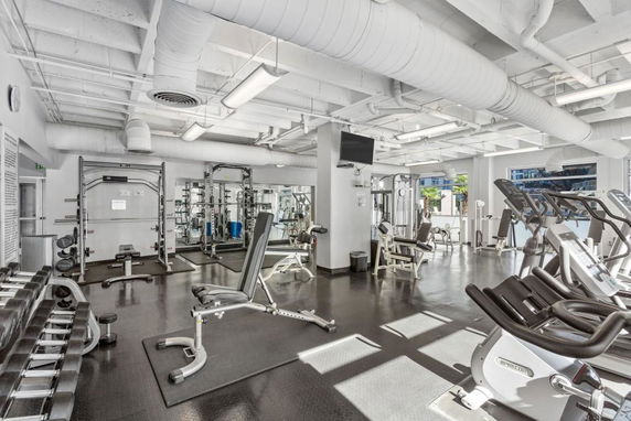 Interior of a gym with exercise equipment and large windows.