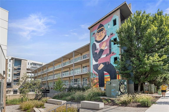 Front view of a multi-story building with a large mural on the side.