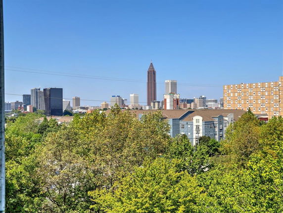 Wide angle view of cityscape with tall buildings and trees in the foreground.