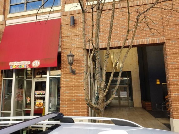 Front view of a commercial building with a red awning and brick exterior.