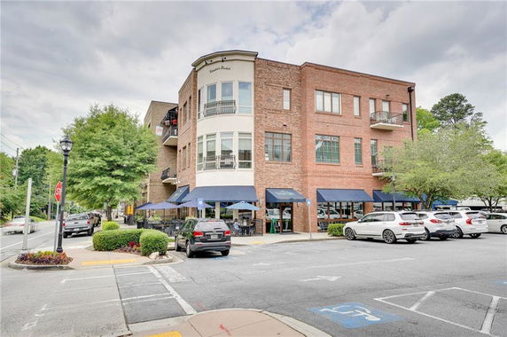Front view of a multi-story brick building with large windows and a street-level commercial space.