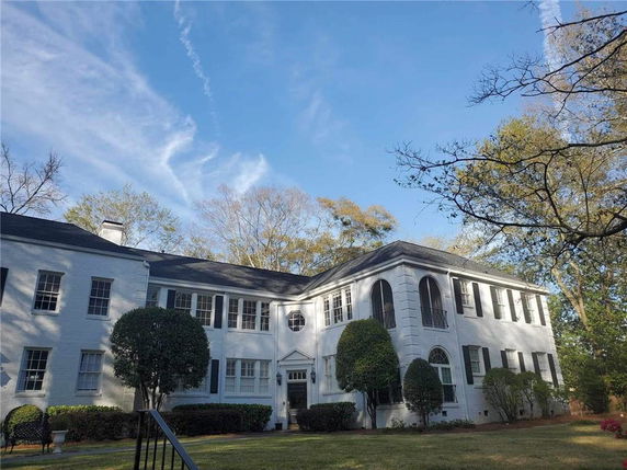 Front view of a two-story house with white brick exterior and black shutters.