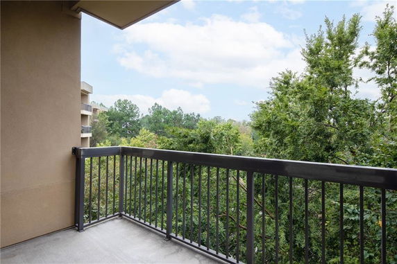 View from a balcony showing surrounding trees and adjacent building.
