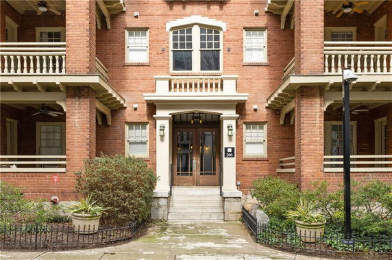 Front view of a multi-story brick building with balconies and a central entrance.