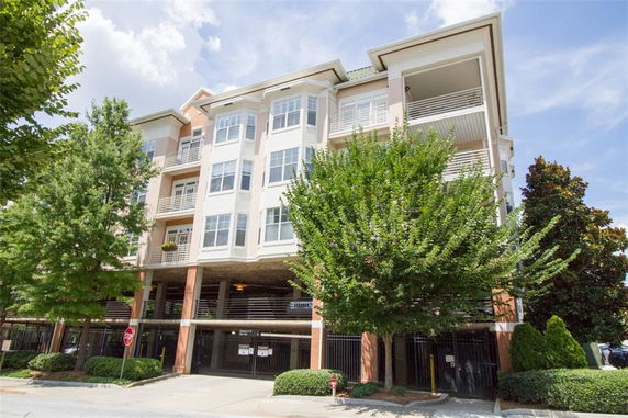 Front view of a multi-story apartment building with a parking area at the ground level.