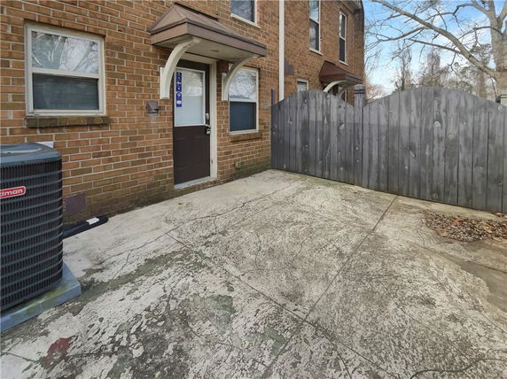 Side view of a brick townhouse entrance with a wooden gate.