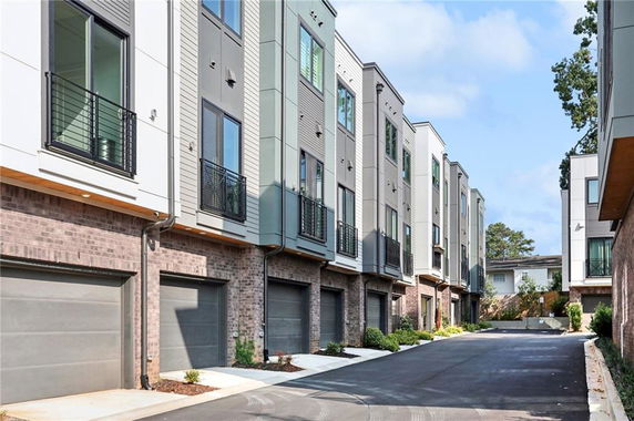 Front view of a row of modern multi-story townhouses with garages.
