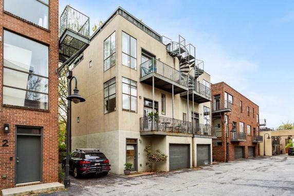 Front view of a multi-story building with balconies and spiral staircase.